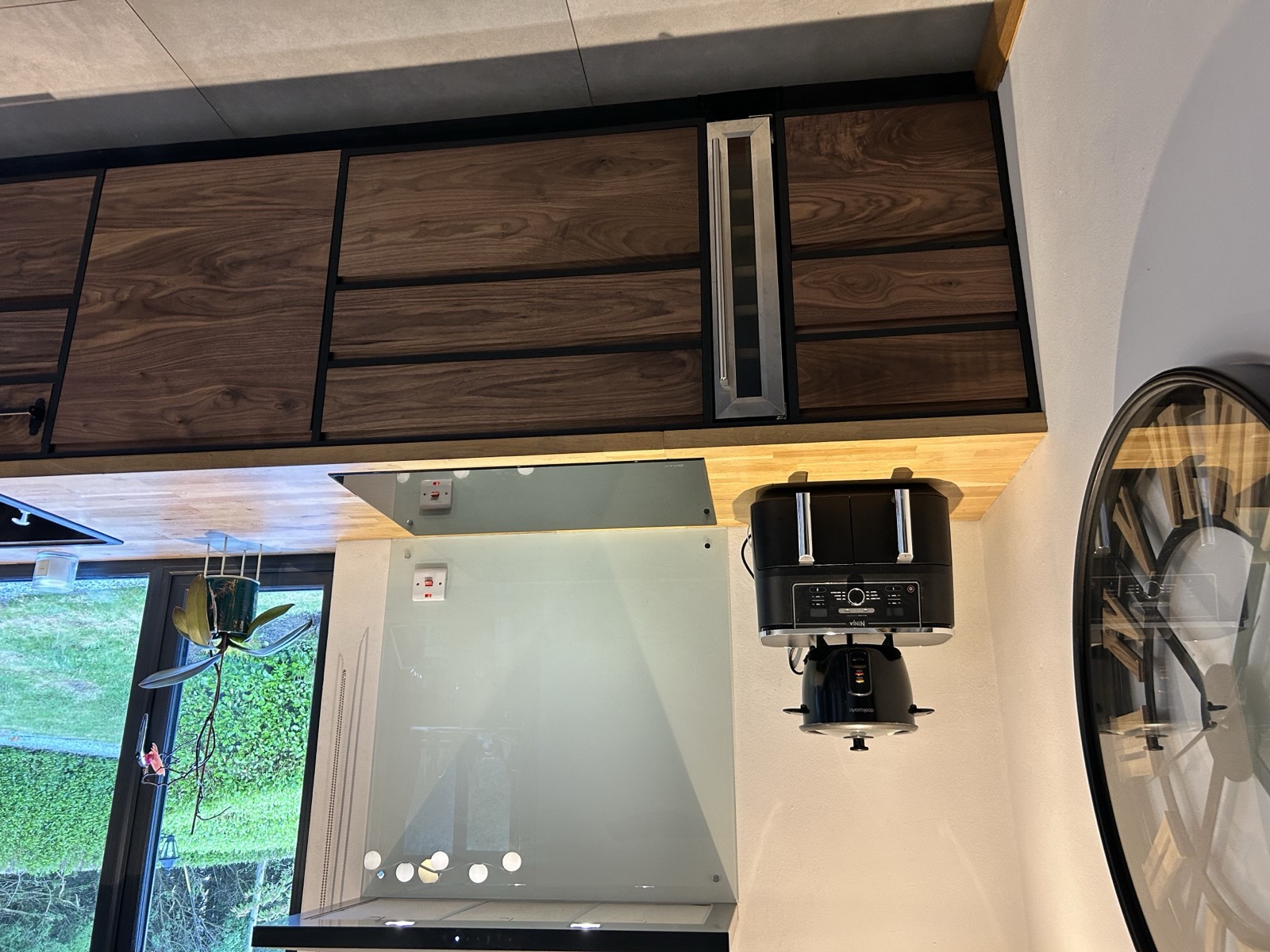 Walnut wall cabinets framed in black painted plywood with integrated wine cooler