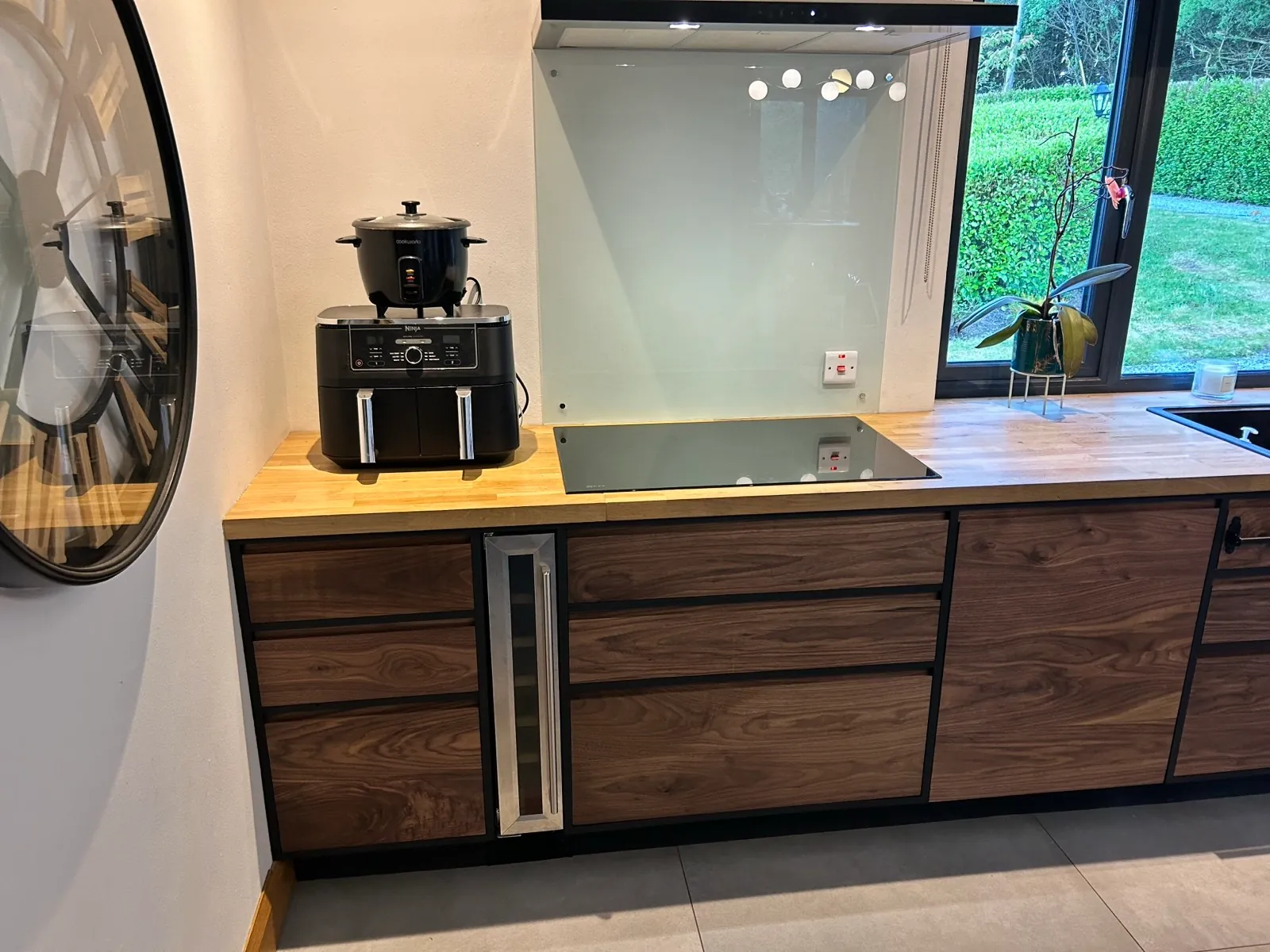 Walnut wall cabinets framed in black painted plywood with integrated wine cooler