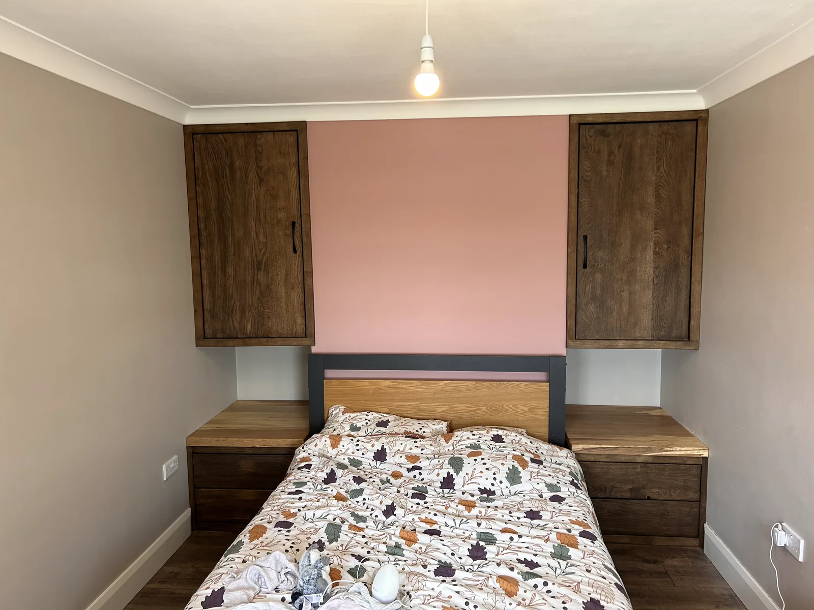 Built-in alcove wardrobes in dark stained oak either side of the bed above matching bedside lockers