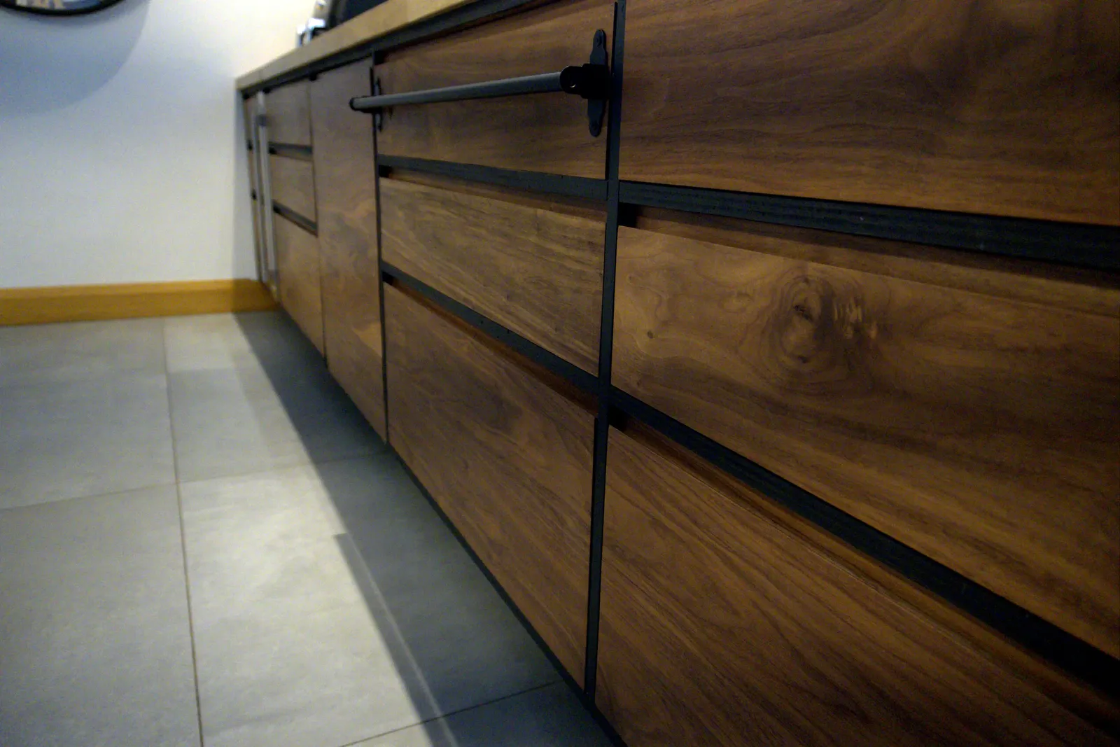Close-up of walnut drawer fronts with a black face frame and rail