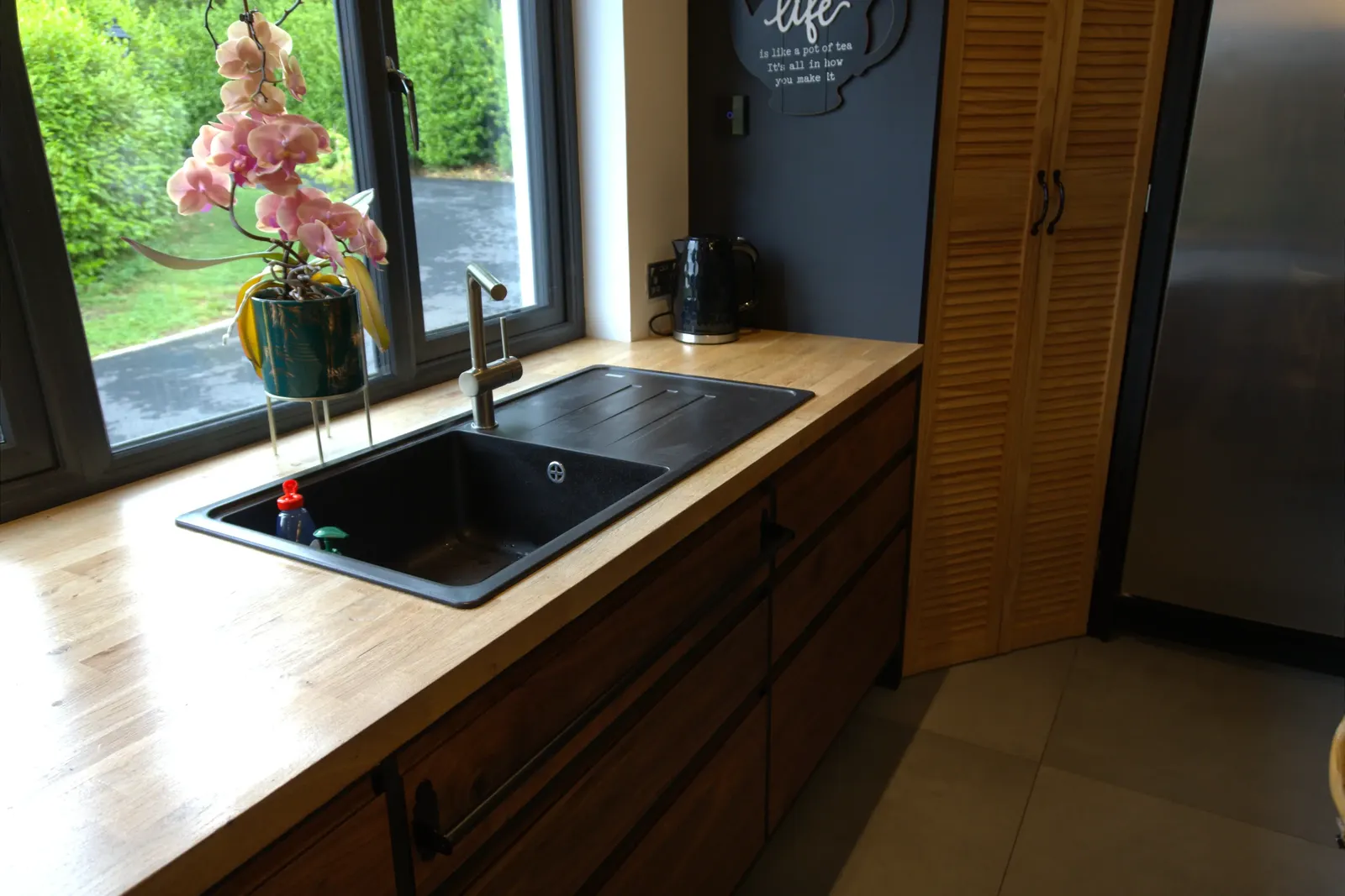 Black composite sink and brushed steel tap set into an oak worktop