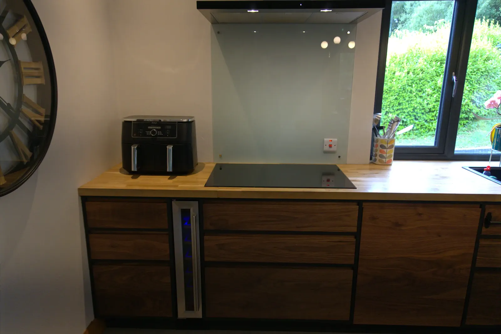 Induction hob with glass splashback and slimline wine cooler set into walnut units