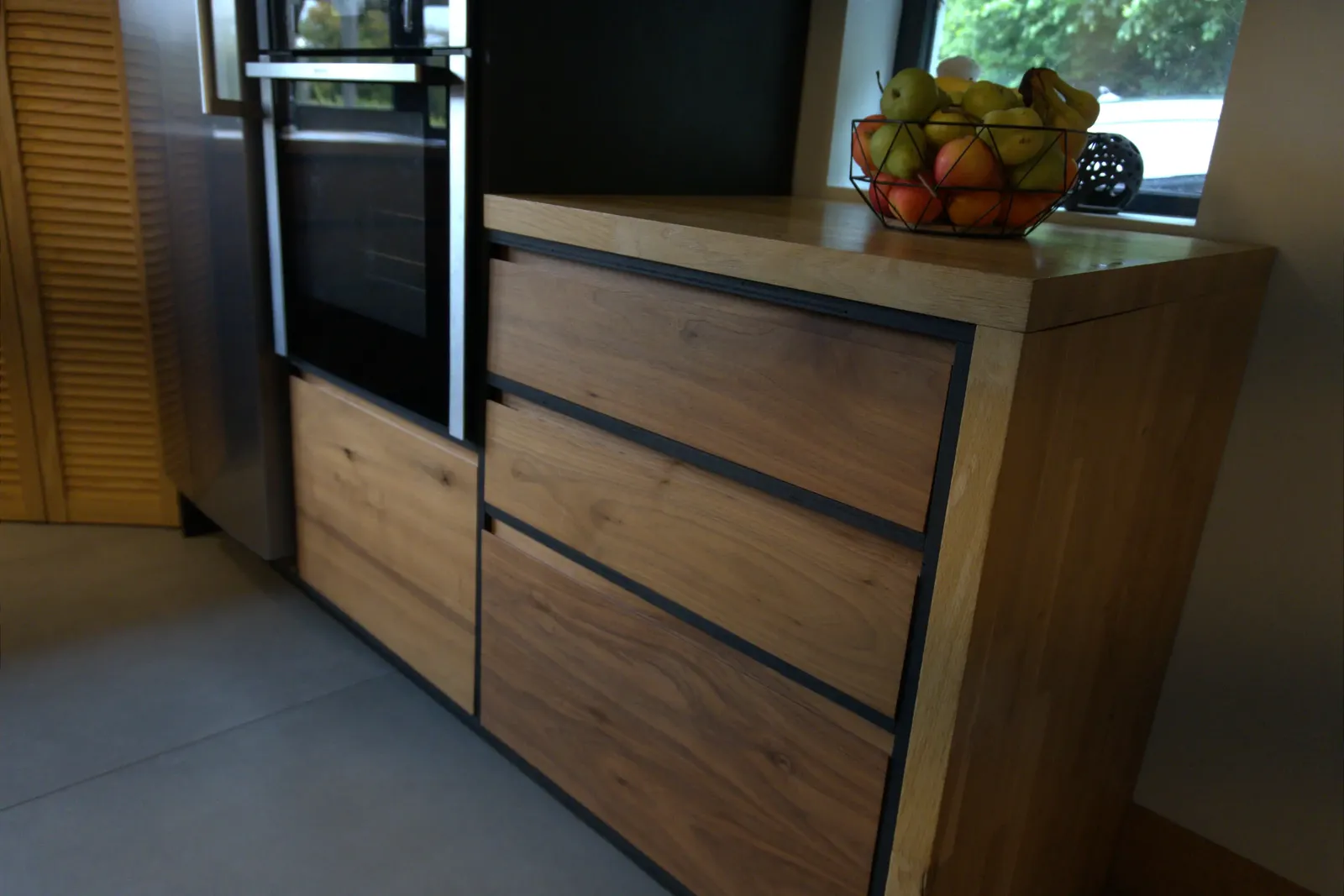Oak-topped walnut drawer cabinet beside the integrated oven