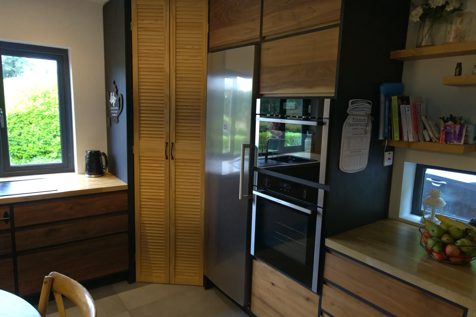 Full kitchen view with integrated fridge, double oven and louvred pantry doors