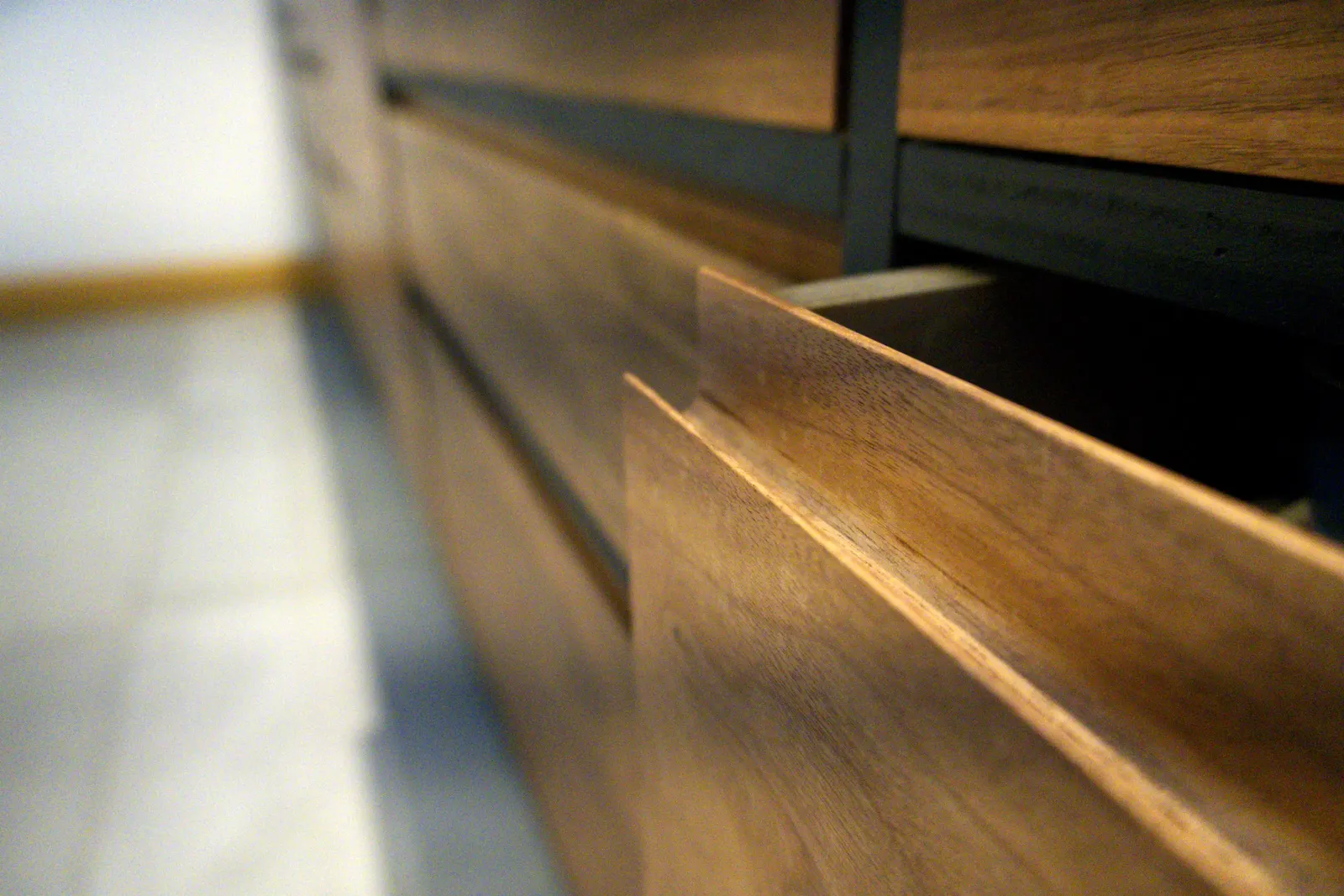 Detail of an integrated pull shaped into a walnut drawer edge