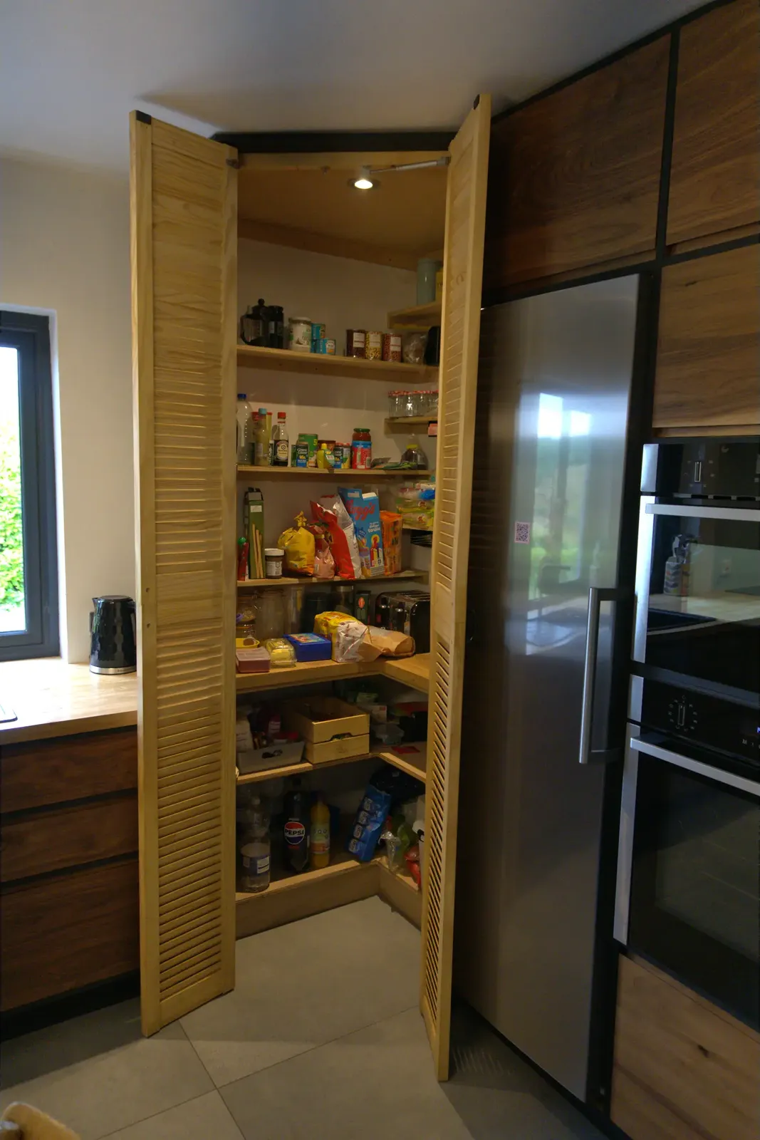 Corner pantry with louvred doors open showing fitted shelving